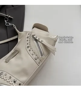 Détail du sac moto beige montrant le cuir souple et les rivets métalliques élégants