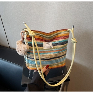 Close-up of rainbow striped woven bucket bag with cute bear charm and drawstring strap