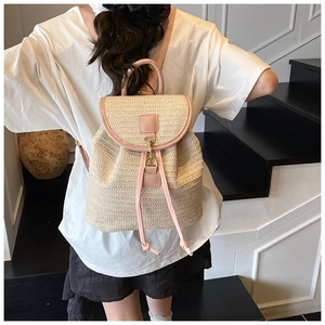 Close-up of the beige woven straw texture and pink leather straps of the backpack