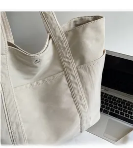 Detail of minimalist beige canvas tote bag with KFR lettering in a workspace setting