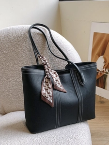 Minimalist black pebbled leather tote bag with contrast stitching and decorative scarf
