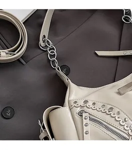 Détail du sac en cuir crème avec rivets, chaîne argentée et bords découpés ondulés
