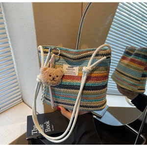 Detailed close-up of rainbow straw woven bucket bag with cute bear charm and white handle