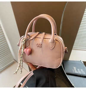 Détail du sac à bandoulière rose en cuir verni avec charm cœur et foulard en soie décoratif