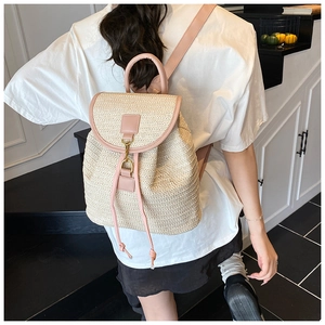 Detail shot of the cream woven straw backpack with pink leather straps worn on a model