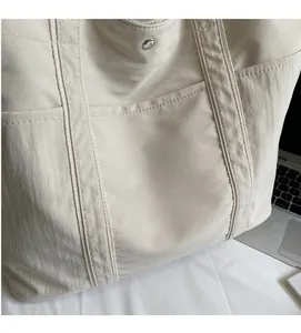 Detail of off-white canvas tote bag featuring KFR print and metallic snap button