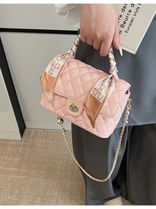 Pink quilted crossbody bag with gold hardware and silk scarf wrapped handle held by model