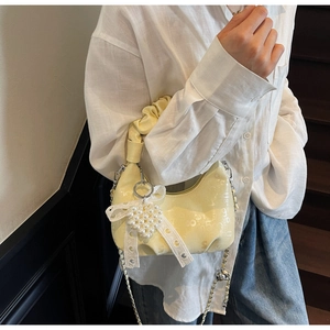 Detail of cream pleated handbag with pearl heart charm and silver chain strap