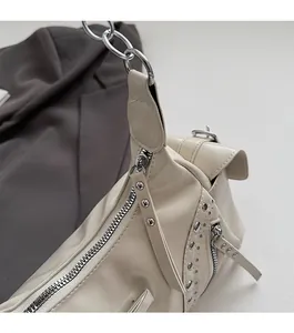 Détail des rivets argentés et du zip métallique lisse sur un sac porté épaule blanc