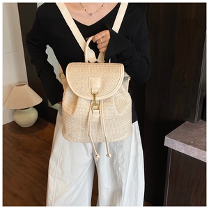 Detail of cream straw woven backpack with leather straps and gold metal lock buckle