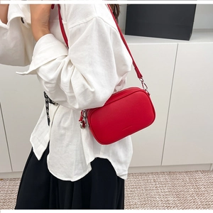 Borsa a tracolla rossa in pelle martellata indossata con camicia bianca e gonna nera chic