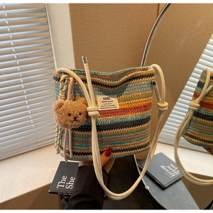Close-up of colorful woven bucket bag featuring vibrant stripes and plush bear charm