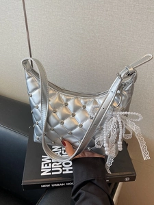 Sac à bandoulière matelassé argenté avec strass et breloque perle dans un décor chic