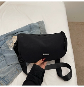 Detail view of black crescent moon crossbody bag with adjustable wide shoulder strap