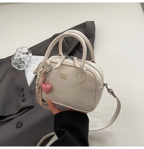 Détail du sac à main beige avec logo PAN TOR et pendentif en forme de cœur