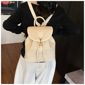 Detail of woven straw backpack showing creamy texture and synthetic leather strap details