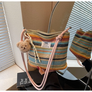 Macro detail of multi-color striped woven bucket bag with pink strap and bear charm