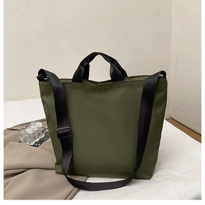 Detail of dark green nylon tote bag with black handles and adjustable shoulder strap