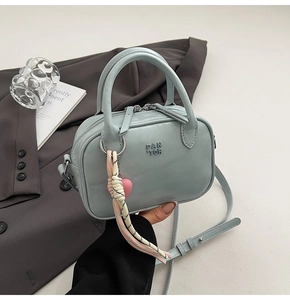 Détail du sac à main en cuir bleu clair avec double fermeture et breloque coeur