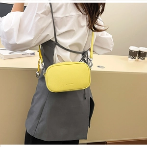 Modella che indossa una borsa a tracolla in pelle giallo brillante con tracolla
