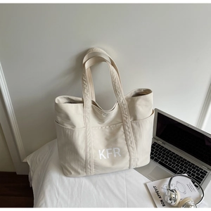 Detail shot of a beige canvas tote bag with KFR print and functional outer pockets