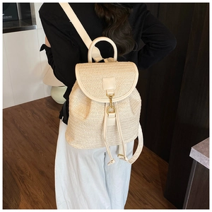 Detailed texture of beige woven straw backpack featuring gold ring buckle and drawstrings