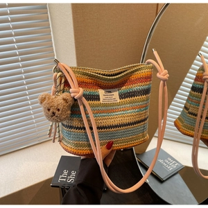 Detail of colorful woven straw bucket bag with striped texture and plush bear charm