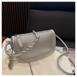 Vue détaillée du sac selle argenté grainé avec poignée tressée et pendentif métallique