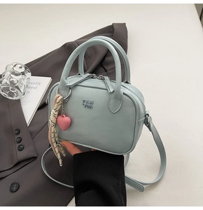 Gros plan du mini sac Boston bleu clair avec logo PAN TOR et accessoire cœur rose