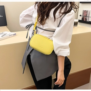 Dettaglio di una borsa a tracolla in pelle giallo brillante con motivo litchi e cinturino