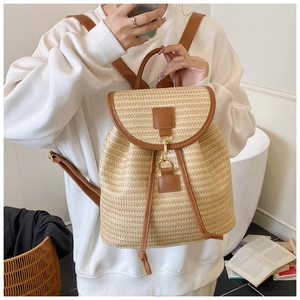 Detail of straw backpack featuring brown leather straps and gold metal hook closure