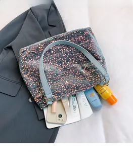 Detail of sequin tote bag with light blue straps and golden metal rings showing storage