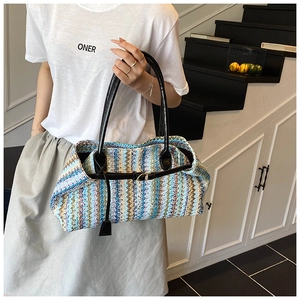 Detail of colorful woven tote bag featuring wavy patterns and black leather handles