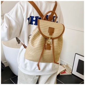 Straw woven backpack with brown leather trim shown in a cozy indoor lifestyle setting