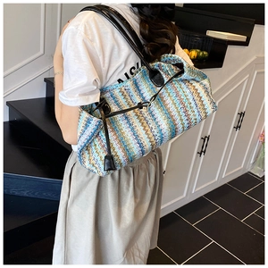 Detail of colorful woven shoulder bag with wavy stripes and black leather handles