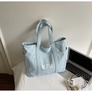 Close-up of light blue canvas tote bag with white KFR logo and magnetic buckle closure