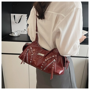 Détail d'un sac à bandoulière en cuir bordeaux avec rivets argentés et pampilles décoratives