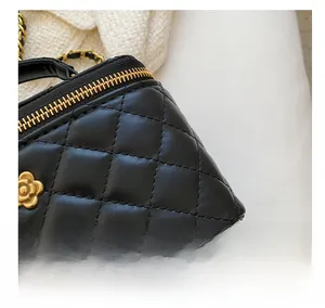 Detail of black quilted leather bag with camellia golden logo and metal zipper