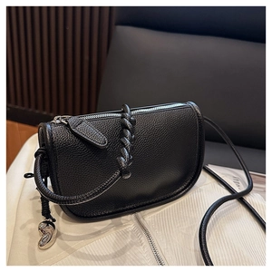 Vue détaillée du sac besace en cuir grainé noir avec pendentif argenté et sangle tressée