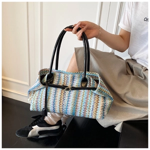Detail of multi-color woven straw bag featuring blue wave patterns and black leather strap