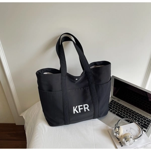Black canvas tote bag with KFR print shown with laptop and headphones for work