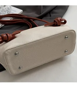 Détails du fond du sac cabas beige tissé avec clous en métal argenté et anse en cuir