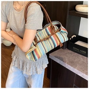 Detail of colorful striped woven tote bag with brown leather strap worn by a model