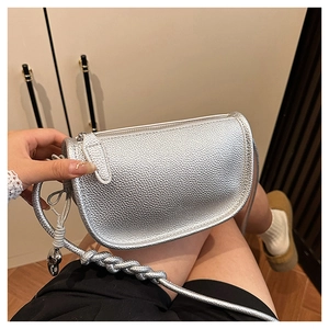 Détail du sac selle argenté avec texture grainée et bandoulière tressée épaisse