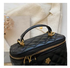 Detailed macro view of quilted black leather mini bag with golden camellia zipper puller
