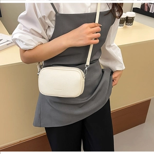 Dettaglio di una borsa a tracolla bianco crema in pelle martellata con dettagli argento