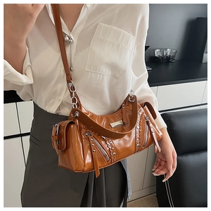 Détail d'un sac bandoulière en cuir marron brillant avec rivets et fermetures