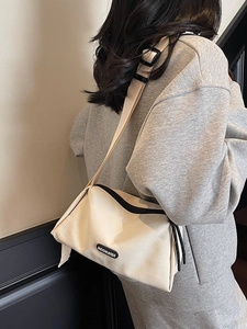 Sac bandoulière polyvalent en toile crème avec large sangle et détails noirs contrastés
