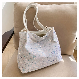 Detail of colorful sequins on white fabric tote bag with elegant golden hardware
