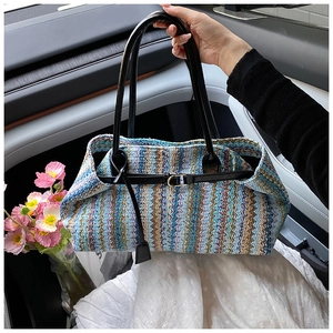 Close-up of woven straw shoulder bag featuring herringbone patterns and black leather strap